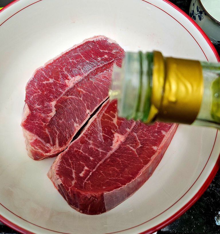 Rubbing olive oil on the flat iron steak Adding olive oil to flat iron steak