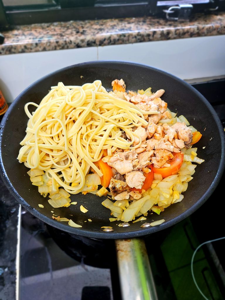 Tossing pasta and salmon into the sauce Adding pasta and salmon