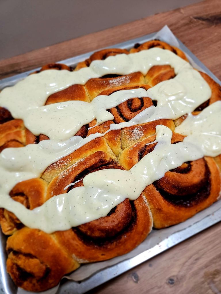 Applying the glaze over warm cinnamon rolls.