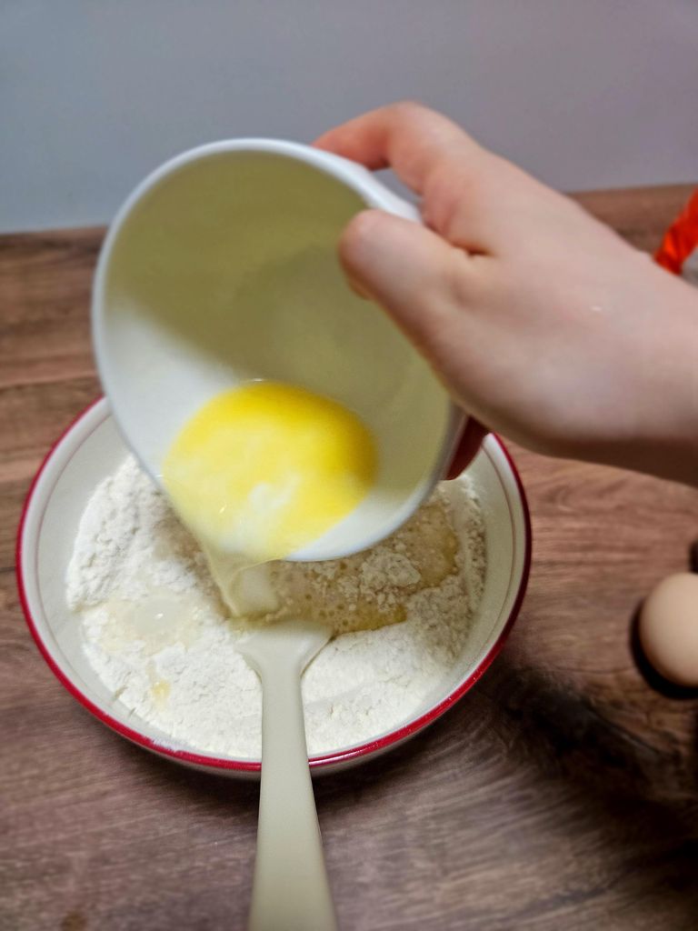 Pouring wet ingredients into dry mixture.