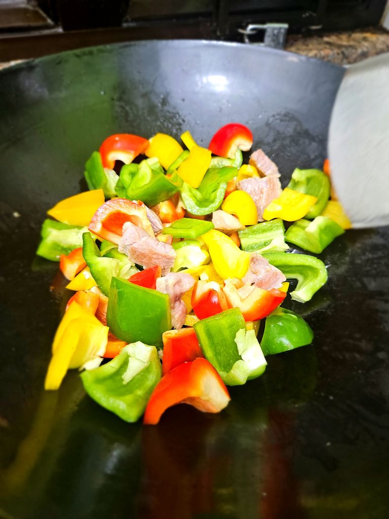 Adding the colorful bell peppers to the wok